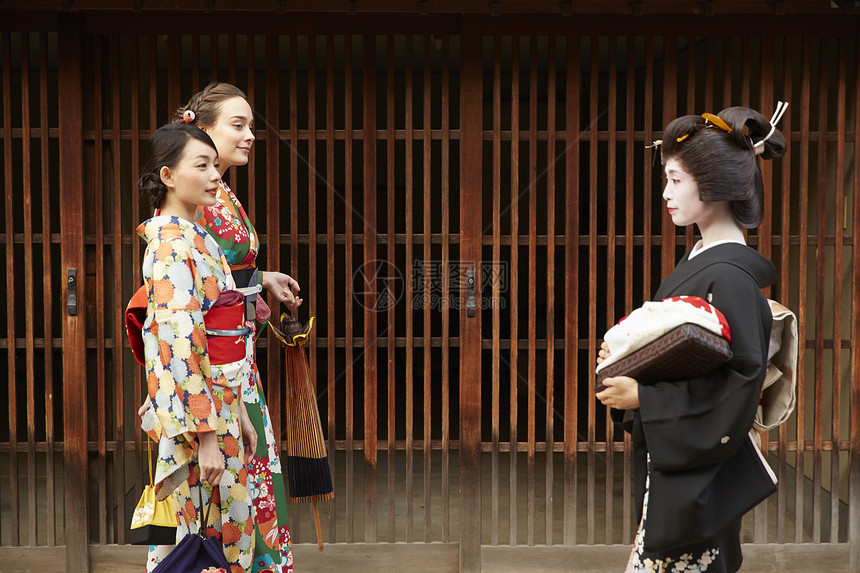 茶屋町穿着和服的女人和艺伎面对面走过图片