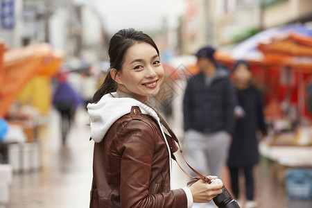 美女手拿相机逛集市图片