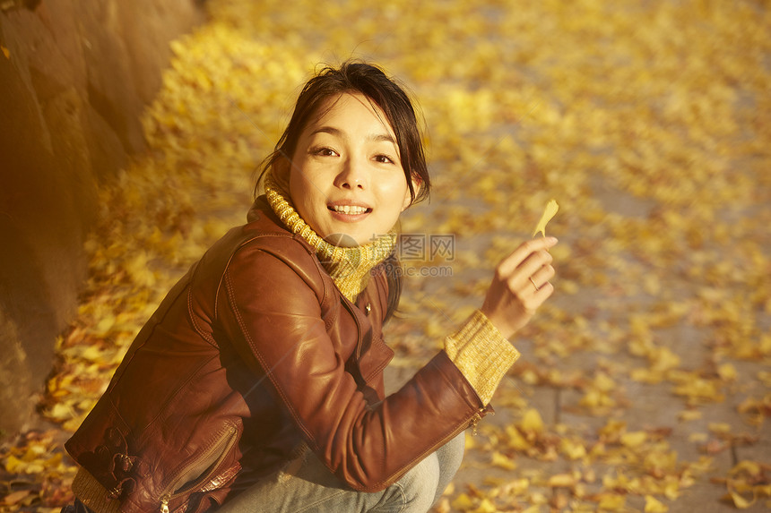 女人蹲在地上拿着银杏叶图片