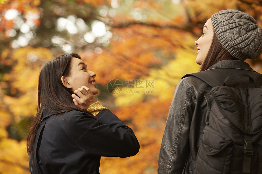 在红枫林下开心聊天的两位美女图片