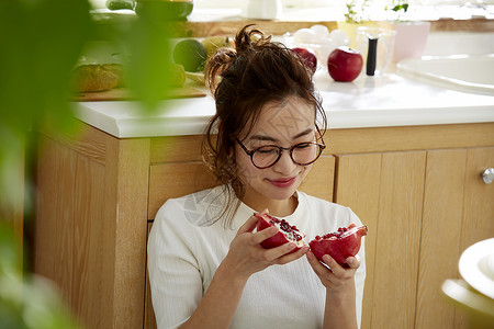 在窗边料理台蹲下看切开的石榴的女人图片