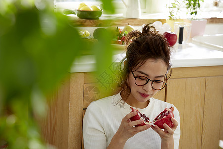 在窗边料理台蹲下看切开的石榴的女人图片