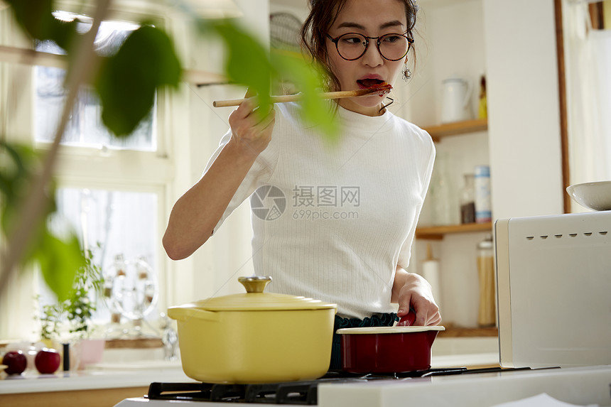 居家的美女正在品尝菜品口味图片