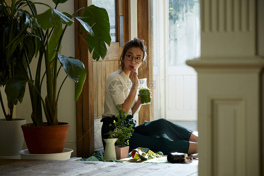 坐在院子里晒太阳喝饮料的时髦美女 图片