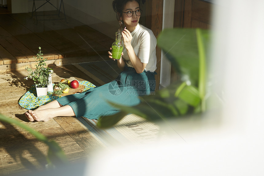 坐在院子里晒太阳喝饮料的时髦美女 图片