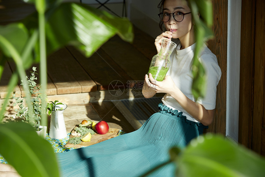 坐在院子里晒太阳喝饮料的时髦美女 图片