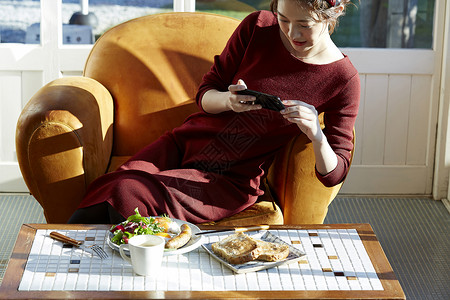 女人拿着手机给桌上的食物拍照图片