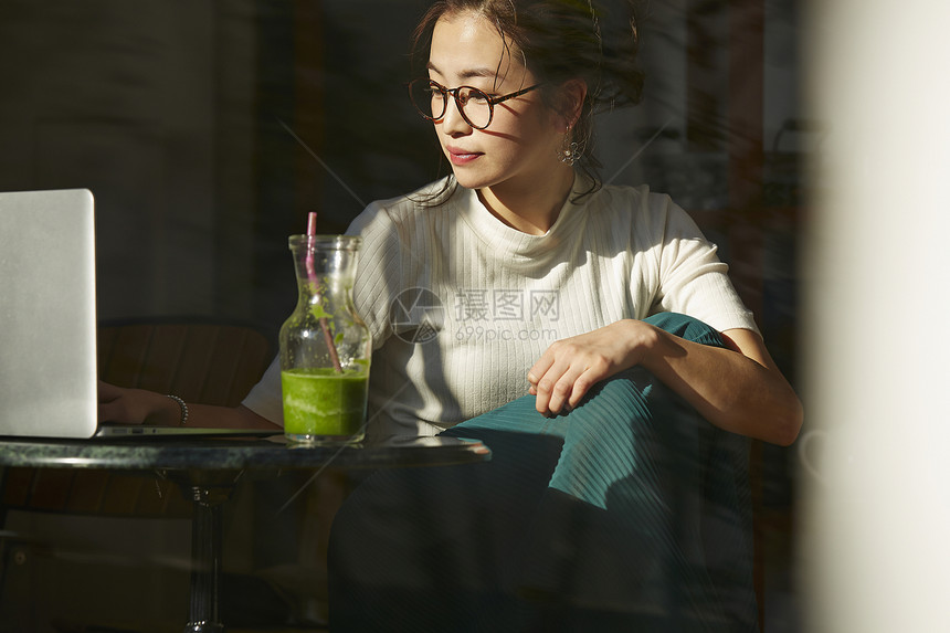 坐在桌边喝奶昔工作的女人图片