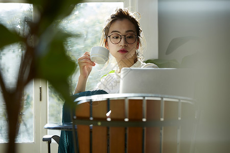 女人坐在窗边的桌上喝咖啡工作图片