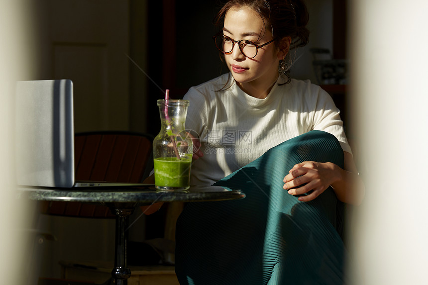 女人坐在窗边的桌上喝奶昔工作图片