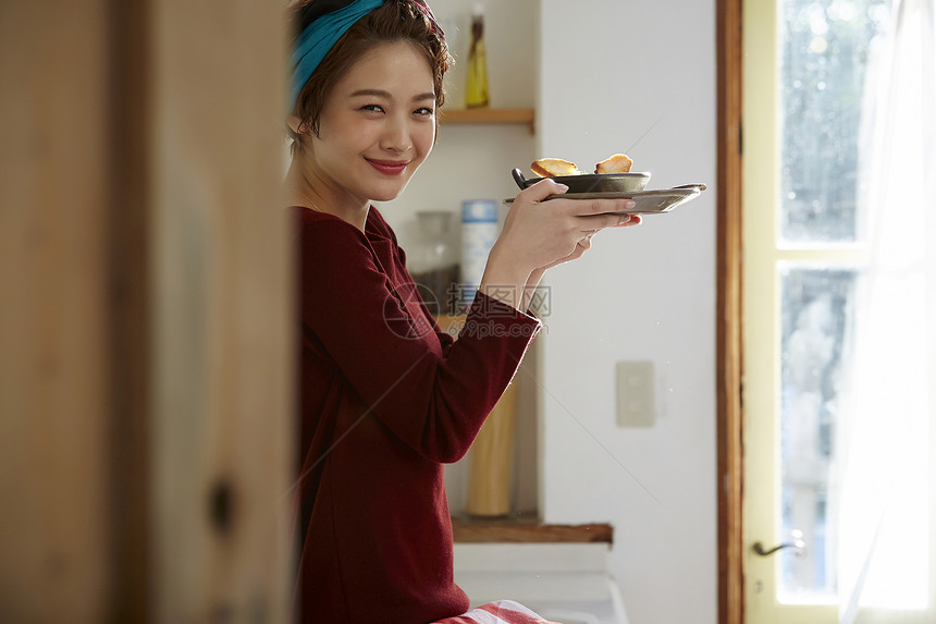 坐在料理台上看着刚刚做好的饭微笑的女人图片