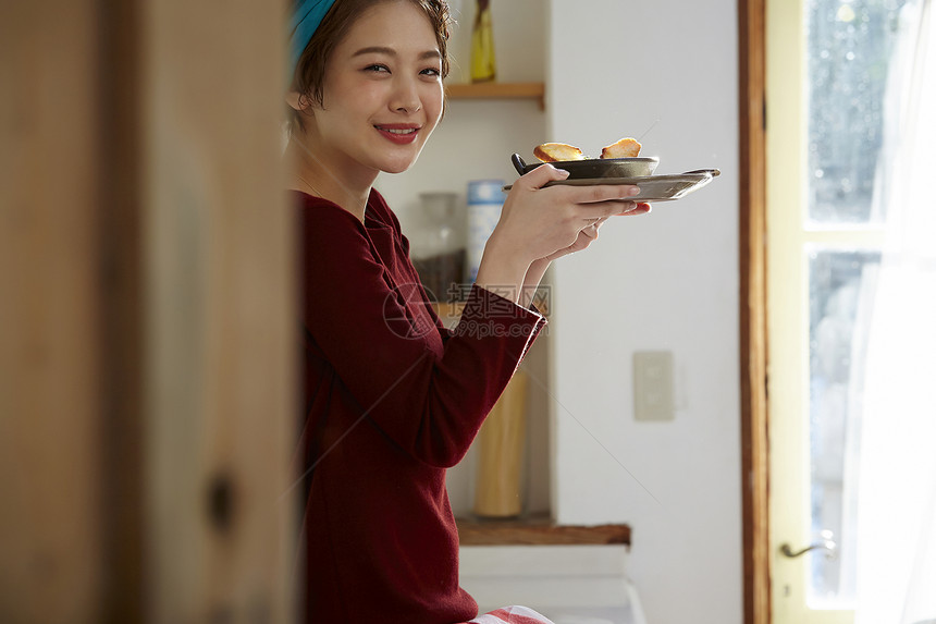 坐在料理台上看着刚刚做好的饭微笑的女人                              图片