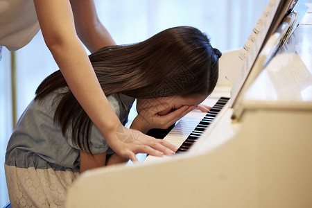 钢琴开课了老师看着钢琴前哭泣的女孩背景