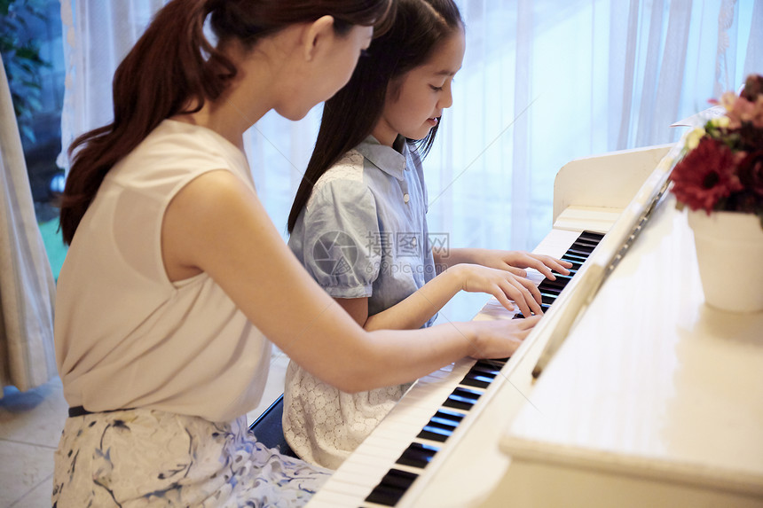 钢琴老师在指导女孩练琴图片