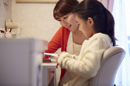 老师辅导在家里做假期作业的女孩高清图片