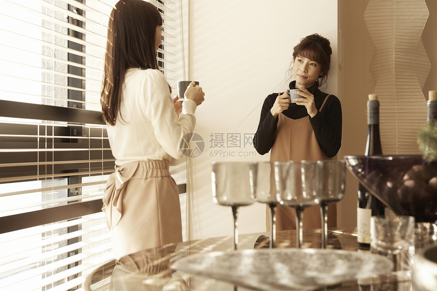 在公寓窗边和朋友喝酒聊天的女人图片