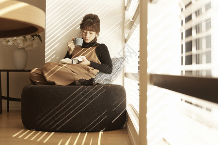 茶椅坐在公寓窗边沙发上看书喝咖啡的女人背景