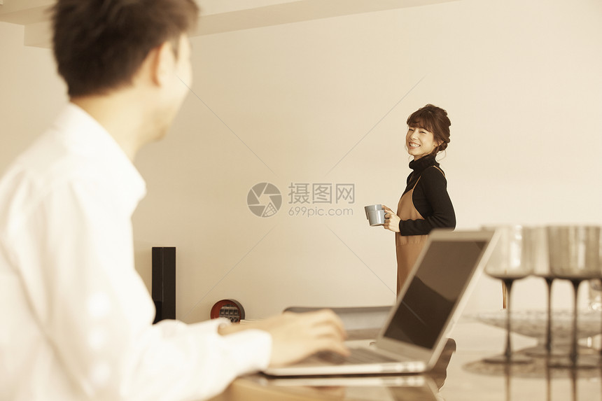 男人坐着用电脑工作女人端着咖啡站着图片