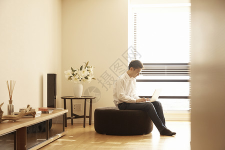 男人坐在沙发上喝咖啡用电脑工作图片