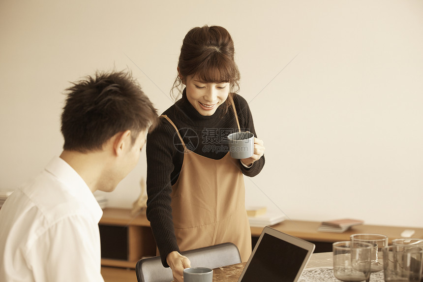 男人坐着用电脑工作女人端着咖啡站着图片