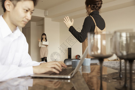 男人坐着用电脑工作女人招呼客人图片