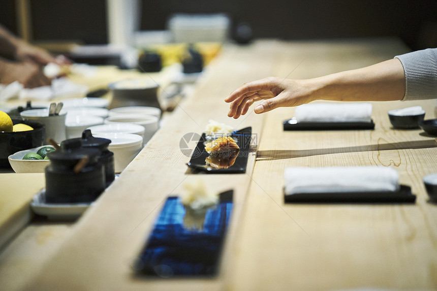 厨师吧做好的寿司放进顾客的盘子里图片