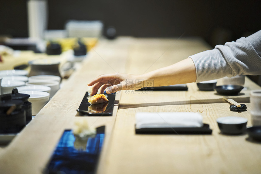 厨师吧做好的寿司放进顾客的盘子里图片