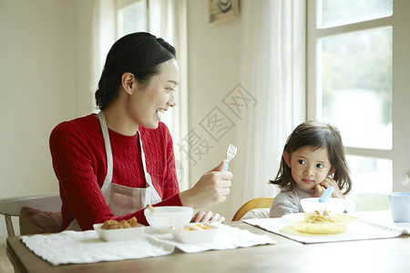 穿围裙母亲保姆在照顾孩子吃饭背景