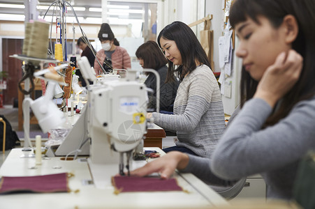 正在手作店里学习制作皮包的学员女孩高清图片素材