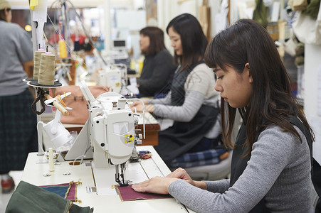 在制作手提包的女缝纫工愉快高清图片素材