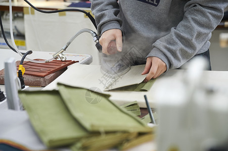 在制作手提包的女缝纫工在熨烫古代高清图片素材