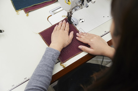 坐下在制作手提包的女缝纫工蓝领工人高清图片素材