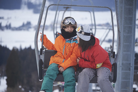 参加俱乐部滑雪活动的情侣坐在缆车上图片