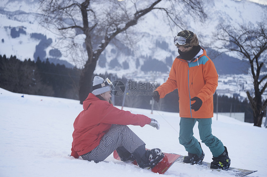 参加俱乐部滑雪活动的情侣在雪地练习图片