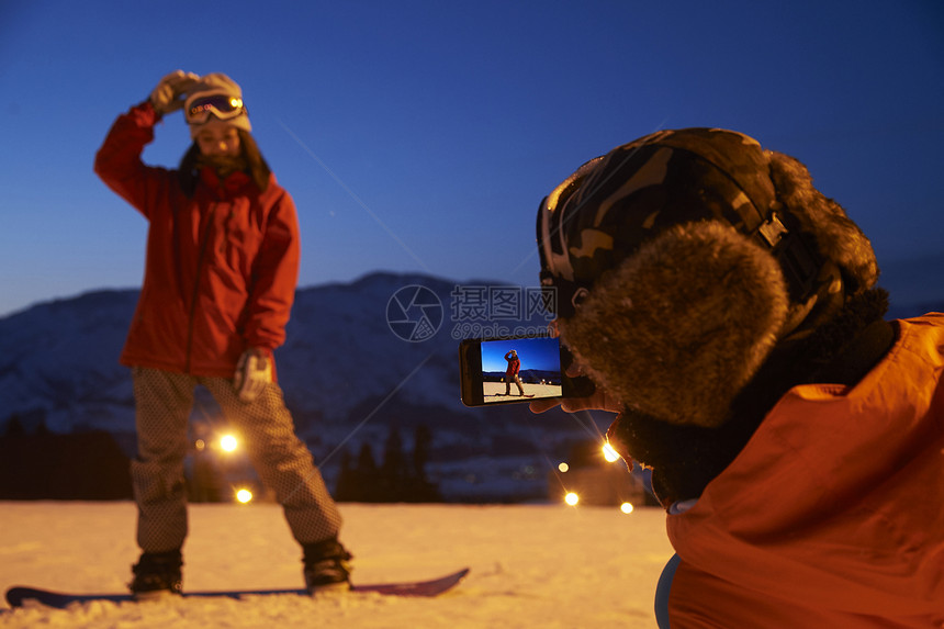 参加俱乐部滑雪活动的男人给女人拍照图片