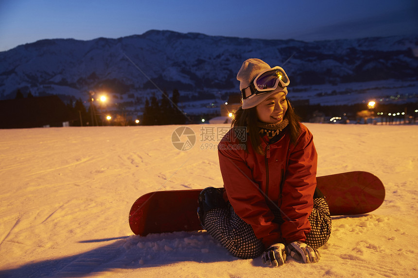 参加俱乐部滑雪活动的女人坐在雪地上微笑图片