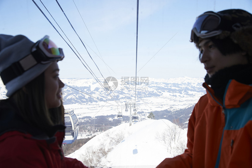 参加俱乐部滑雪活动的情侣在缆车上对视图片