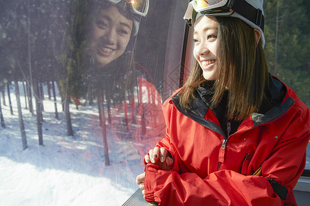 靠着滑雪缆车微笑的年轻女性图片