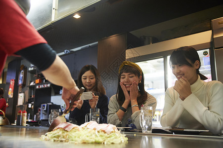 厨师在做广岛烧顾客等着吃并且拍照图片
