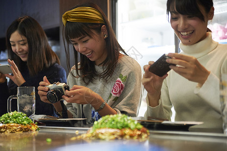 三个女生在开心的拍摄美食图片