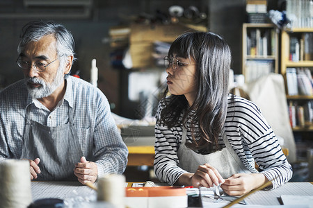 正在装订书本的师徒二人背景图片