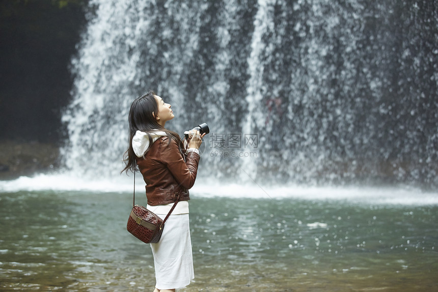 站在瀑布前的女性摄影师图片