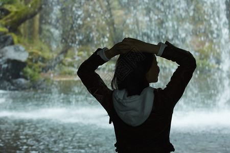 站在瀑布前的女性背影图片