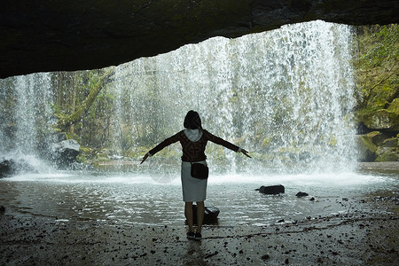 站在岩石下享受瀑布的女人图片