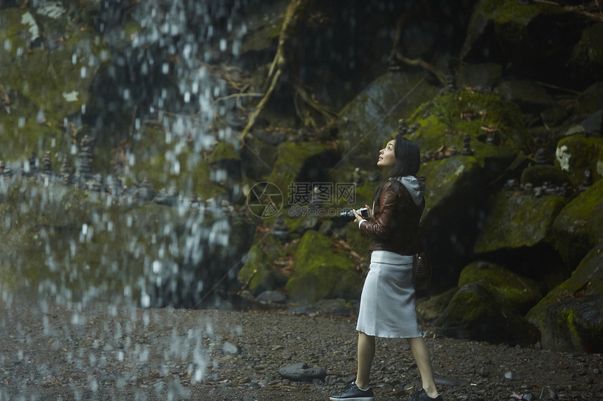 站在岩石下享受瀑布的女人图片