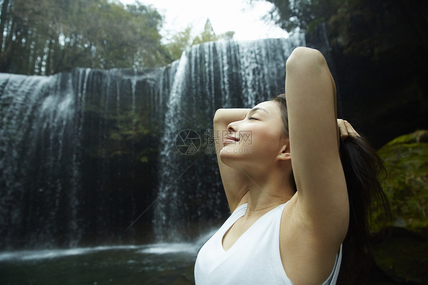 站在小溪边享受瀑布的女人在舒展身体图片