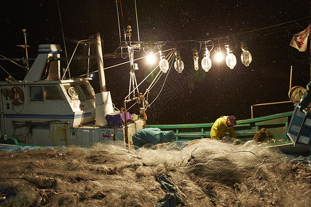 网灯深夜在港口工作的渔民背景