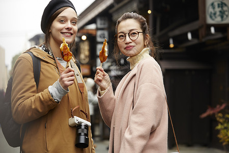 带着相机外国妇女和拿着地图的日本妇女在老街道吃小吃采风岐阜县图片