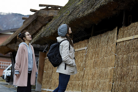 来采风的两个女人在茅草屋前驻足图片