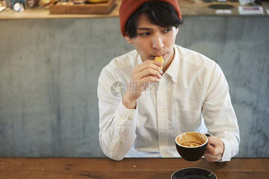 在咖啡馆喝咖啡吃甜品的男青年图片